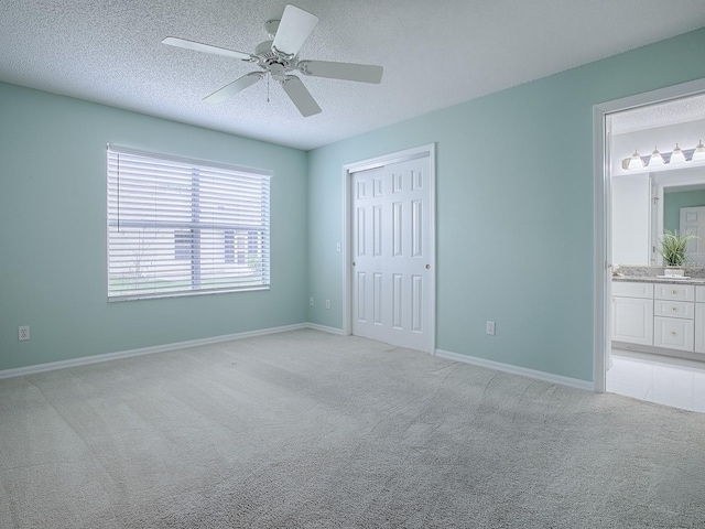 unfurnished bedroom featuring a closet, a textured ceiling, baseboards, and light carpet