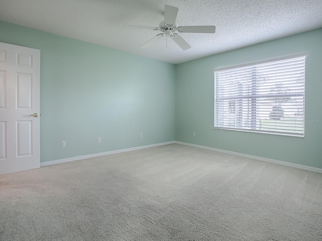 empty room with baseboards, ceiling fan, carpet, and a textured ceiling
