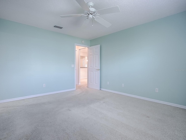carpeted spare room featuring a ceiling fan, a textured ceiling, baseboards, and visible vents