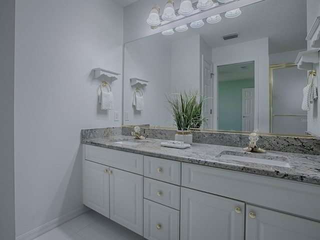 bathroom featuring a stall shower, double vanity, visible vents, and a sink