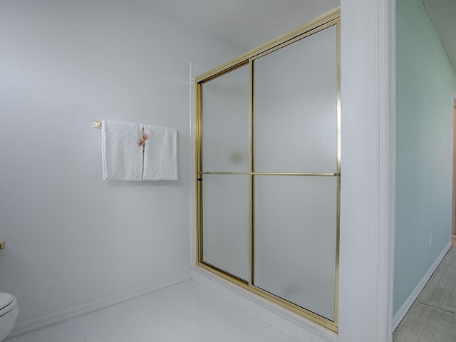 full bath with baseboards, a shower with shower door, and toilet