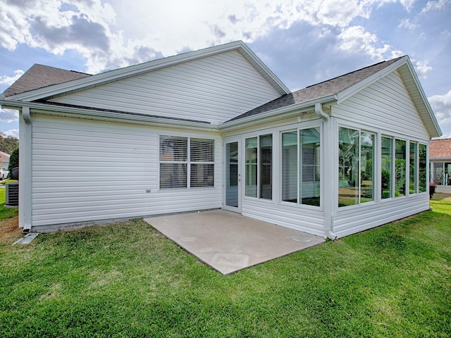 back of house featuring a patio, a sunroom, a shingled roof, and a lawn