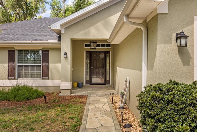 property entrance with stucco siding and roof with shingles