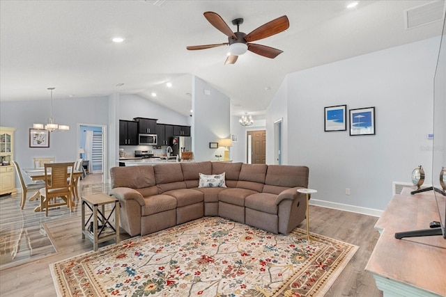 living area featuring recessed lighting, ceiling fan with notable chandelier, baseboards, visible vents, and light wood-style flooring