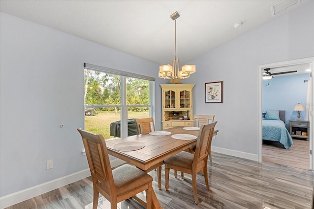 dining area featuring light wood-style flooring, a notable chandelier, baseboards, and vaulted ceiling