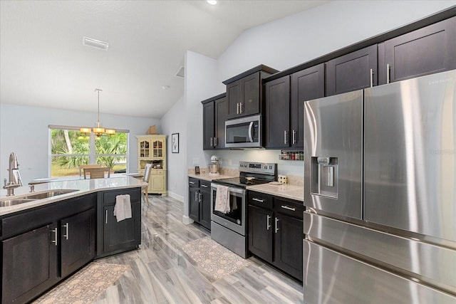 kitchen featuring light countertops, vaulted ceiling, stainless steel appliances, a sink, and visible vents