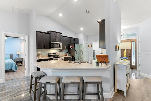 kitchen featuring a sink, stainless steel appliances, a breakfast bar, and light wood-type flooring