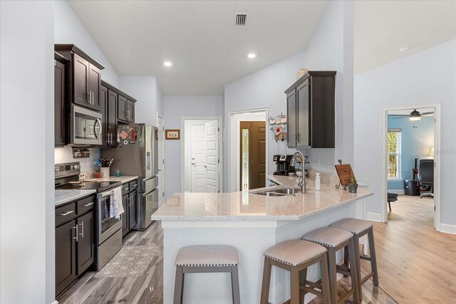 kitchen with a sink, a breakfast bar area, light wood-type flooring, stainless steel appliances, and visible vents