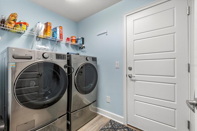 laundry area featuring baseboards, light wood-style flooring, independent washer and dryer, and laundry area