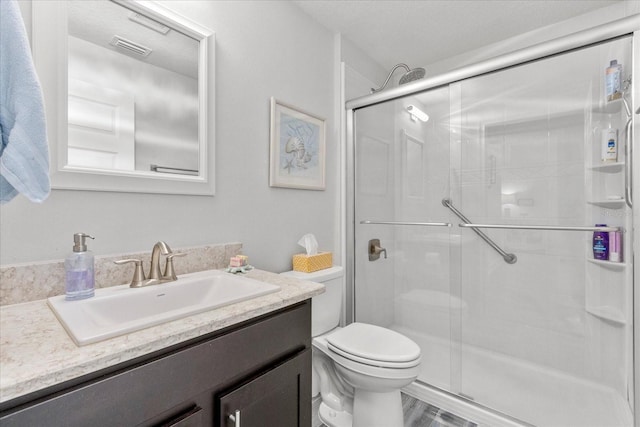 bathroom with a stall shower, visible vents, toilet, and vanity