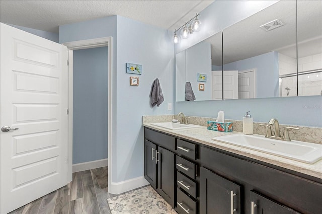 full bath with visible vents, a sink, and a textured ceiling