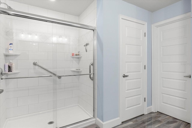 full bathroom with baseboards, a stall shower, and wood finish floors