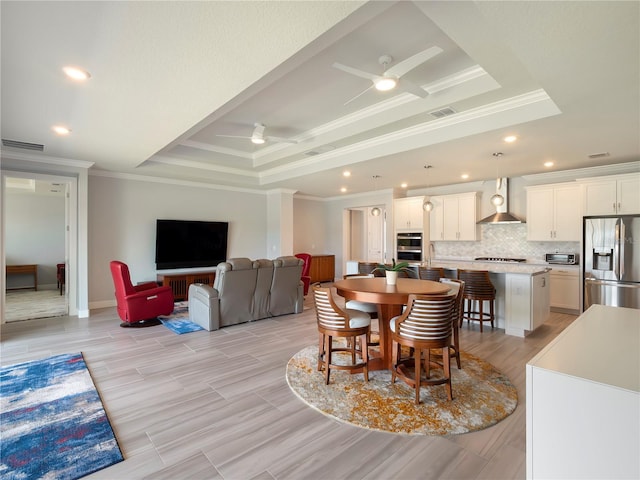 dining room featuring a ceiling fan, crown molding, visible vents, and a raised ceiling