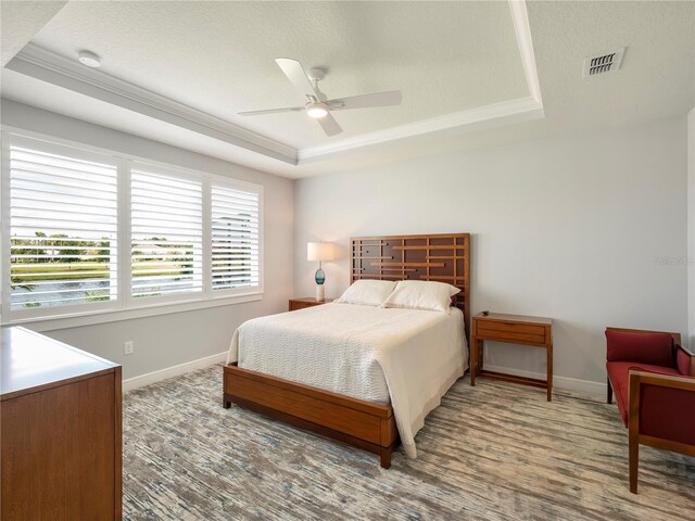 bedroom with visible vents, baseboards, a tray ceiling, and ceiling fan