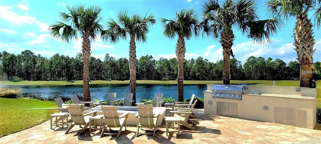 view of patio with grilling area, exterior kitchen, and a water view
