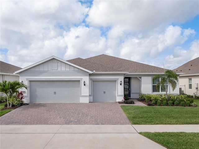 ranch-style home with a front lawn, a garage, decorative driveway, roof with shingles, and stucco siding