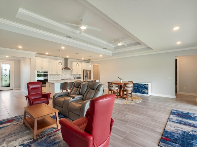 living area featuring a ceiling fan, visible vents, a raised ceiling, and baseboards