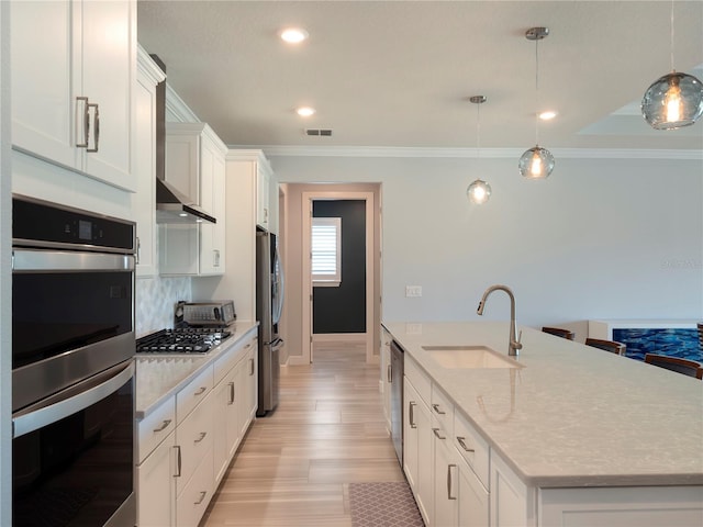 kitchen with a kitchen island with sink, appliances with stainless steel finishes, a sink, white cabinetry, and visible vents