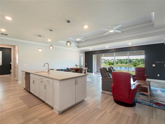 kitchen featuring stainless steel dishwasher, a sink, a raised ceiling, white cabinets, and ornamental molding