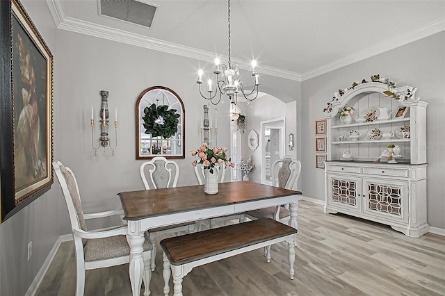 3354 Truluck Pl, Oxford, FL 34484 - dining space featuring crown molding, arched walkways, light wood finished floors, visible vents, and a notable chandelier