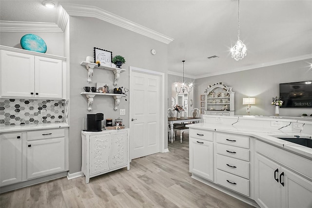 3354 Truluck Pl, Oxford, FL 34484 - kitchen with light countertops, white cabinetry, light wood-style floors, ornamental molding, and an inviting chandelier