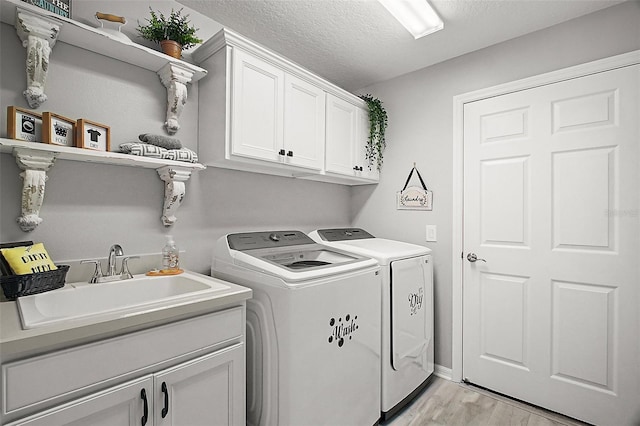 3354 Truluck Pl, Oxford, FL 34484 - laundry room with washer and clothes dryer, a sink, a textured ceiling, light wood-style floors, and cabinet space