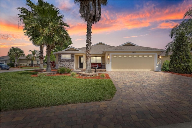 10460 Silver Maple Ave, Oxford, FL 34484 - ranch-style house with an attached garage, decorative driveway, a lawn, stucco siding, and stone siding