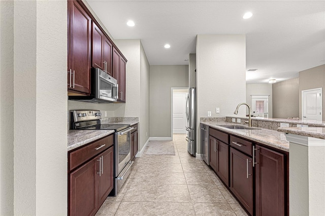 10460 Silver Maple Ave, Oxford, FL 34484 - kitchen with appliances with stainless steel finishes, a sink, light stone counters, a peninsula, and dark brown cabinets