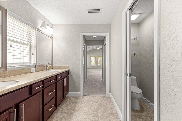 10460 Silver Maple Ave, Oxford, FL 34484 - bathroom featuring a textured ceiling, double vanity, a textured wall, toilet, and ceiling fan