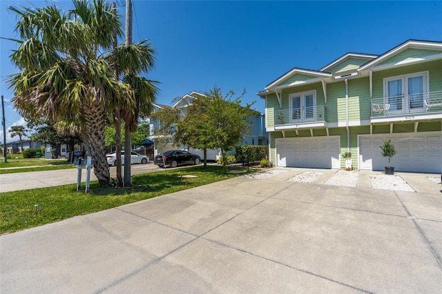 411 S 5th Ave S, Jacksonville Beach, FL 32250 - view of property exterior with french doors, a balcony, driveway, and an attached garage