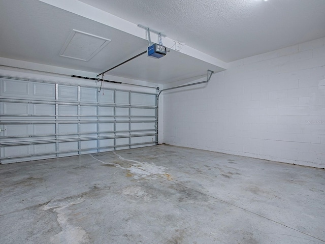 garage featuring a garage door opener and concrete block wall