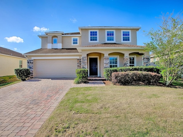 view of front facade featuring a front yard, an attached garage, decorative driveway, and stucco siding