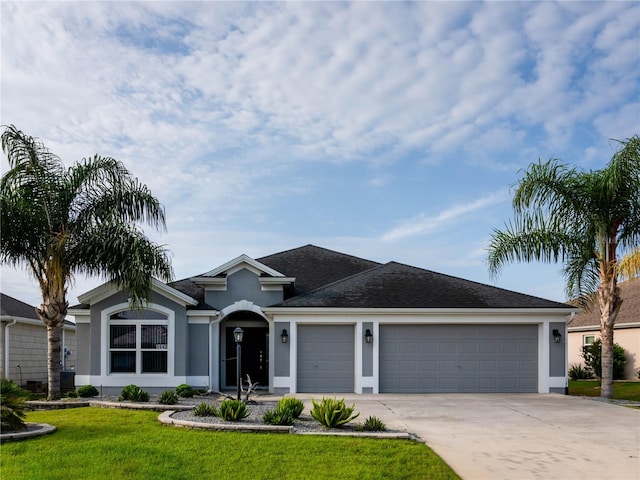ranch-style house featuring a garage, stucco siding, driveway, a front yard, and a shingled roof