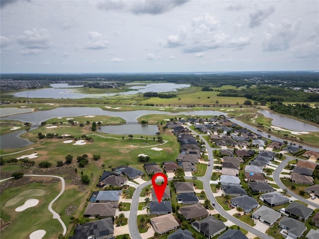 aerial view of property and surrounding area featuring a nearby body of water, a golf course, and nearby suburban area