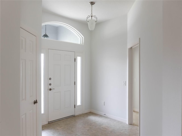 entrance foyer featuring healthy amount of natural light, light tile patterned floors, and a towering ceiling