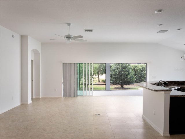unfurnished living room with arched walkways, a ceiling fan, a sink, and vaulted ceiling