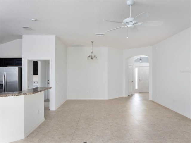 unfurnished living room featuring arched walkways, ceiling fan, light tile patterned flooring, baseboards, and vaulted ceiling