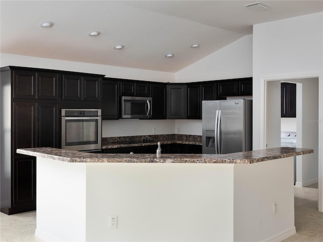 kitchen featuring stainless steel appliances, dark cabinetry, a center island with sink, lofted ceiling, and recessed lighting