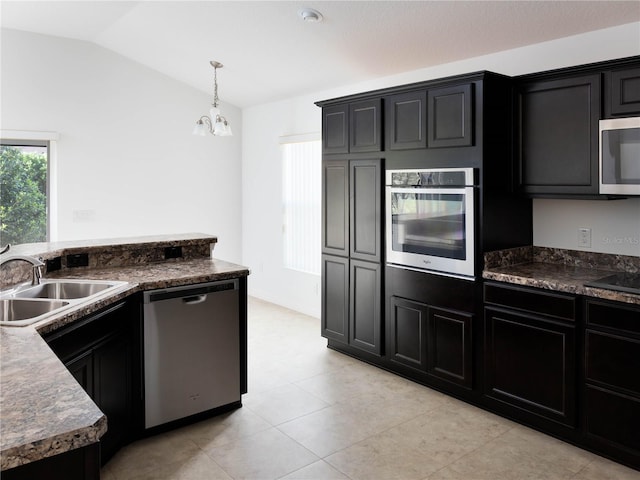 kitchen featuring appliances with stainless steel finishes, a sink, plenty of natural light, dark cabinetry, and lofted ceiling