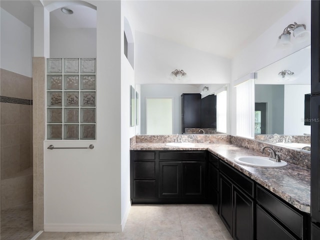 bathroom featuring a walk in shower, double vanity, lofted ceiling, and tile patterned floors