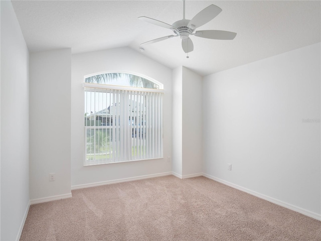 empty room with ceiling fan, light colored carpet, lofted ceiling, and baseboards
