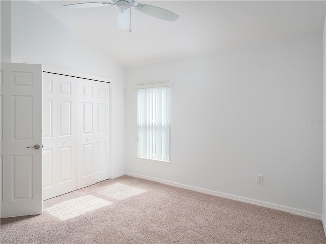 unfurnished bedroom with carpet flooring, lofted ceiling, a closet, baseboards, and ceiling fan