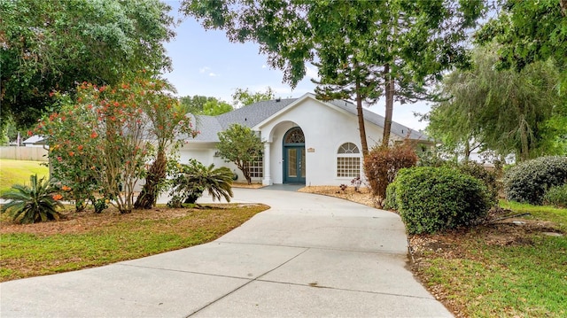 view of front of home with french doors, driveway, a front yard, and stucco siding