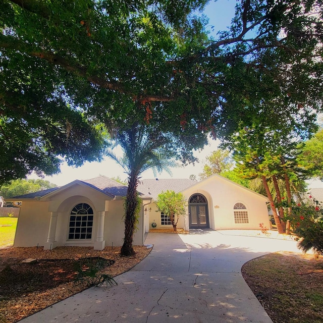 view of front facade featuring a garage, french doors, driveway, and stucco siding