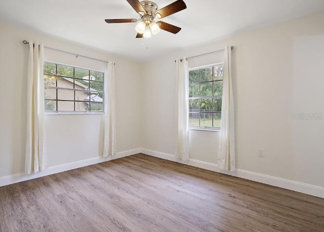 spare room featuring baseboards, ceiling fan, and wood finished floors