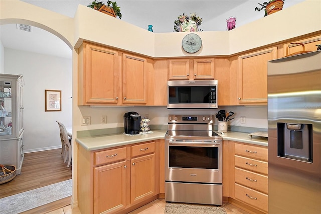 3800 Woodleaf Ct, Leesburg, FL 34748 - kitchen with appliances with stainless steel finishes, light countertops, arched walkways, and light brown cabinets