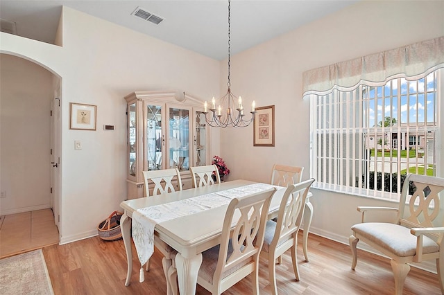3800 Woodleaf Ct, Leesburg, FL 34748 - dining room featuring light wood finished floors, arched walkways, a chandelier, and baseboards