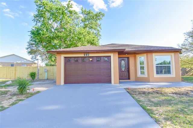 view of front of property with an attached garage, driveway, fence, and stucco siding