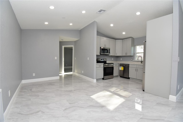 kitchen with appliances with stainless steel finishes, light countertops, a sink, lofted ceiling, and baseboards