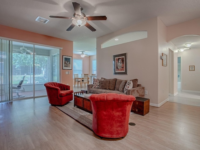 910 Eagles Lndg, Leesburg, FL 34748 - living room featuring a ceiling fan, arched walkways, light wood-type flooring, and baseboards